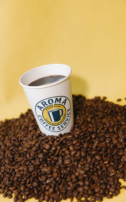 History of Coffee Aroma Coffee Cup in a pile of beans portrait